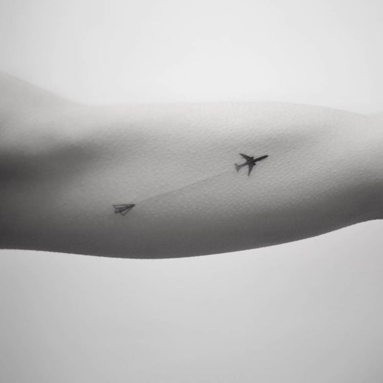 Miniatur Tattoo Oberarm Innenseite Papierflugzeug und echter Flugzeug