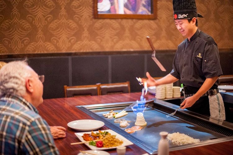 teppanyaki platte plattengriller japanisch kochen exotische gerichte fisch schön präsentiert chefkoch fähigkeiten demonstrieren zwiebel vulkan werfen anzünden