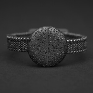 digitale Geldbörse Münze aus schwarz-porösem Aluminium an einem Armband befestigt