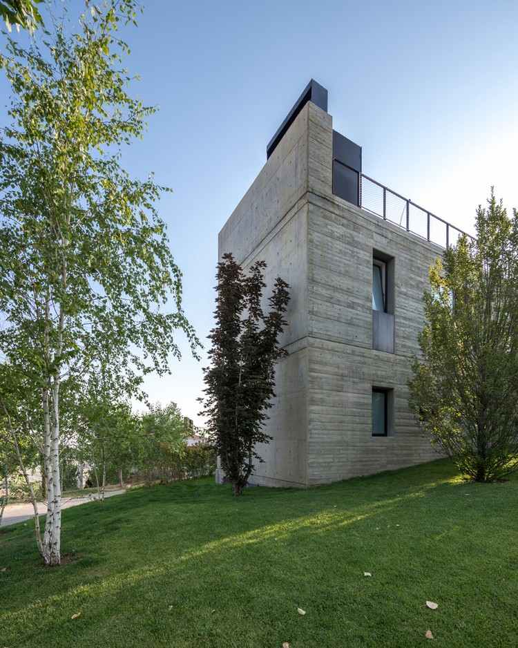 ferienhaus aus beton hanglage rasenfläche bäume