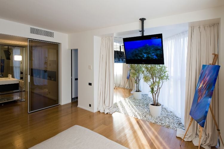 fernsehgerät im schlafzimmer bett mit fernseher design von der decke halterung aufhängen glasschiebetür laminatboden kiesel