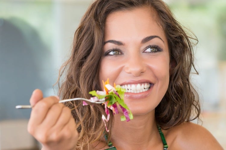 glückliche Frau mit schöner Haut isst Salat Ernährung bei Akne