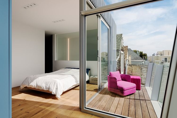 haus mit glasfront dreistöckig neubau design glasfenster terrasse balkon lila sessel bett schlafzimmer laminatboden