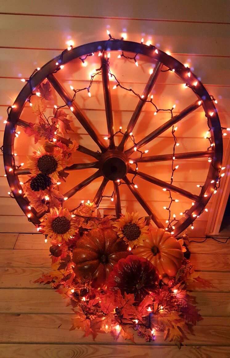 altes Wagenrad dekorieren mit Lichterketten Blumen und Kürbisse aus Kunststoff