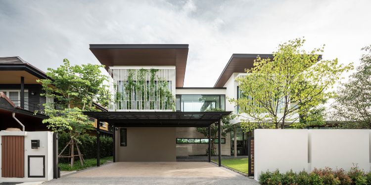 begrünte fassade designer haus moderne architektur glas terrasse natürliche umgebung bäume rasen wachsblume vorderansicht haustür