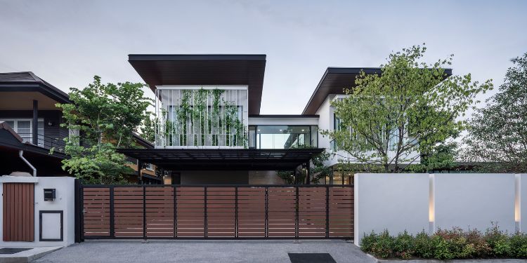 begrünte fassade designer haus moderne architektur glas terrasse natürliche umgebung bäume rasen wachsblume vorderansicht tor garage