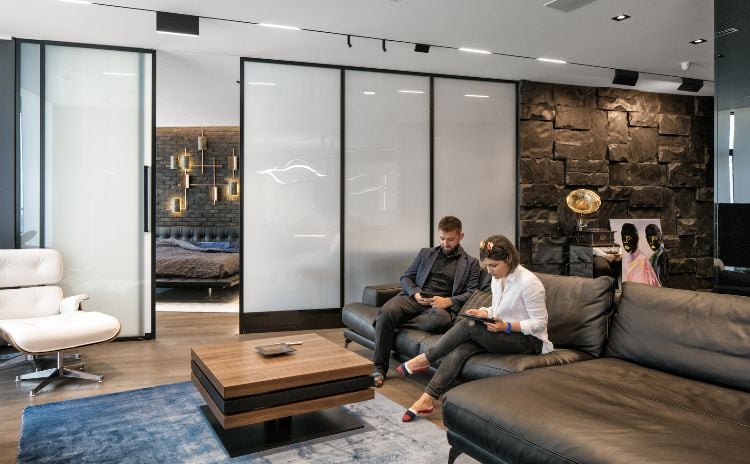 glastrennwand wohnbereich schwarz knopfdruck matt werden ledercouch bewohner sessel designer holztisch teppich