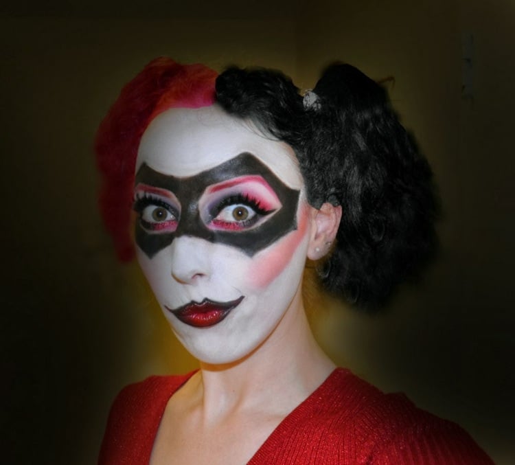 frau für Halloween geschminkt als harlekin augen make up mund schwarz weiß rot
