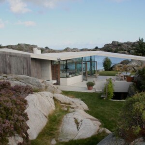 haus mit pultdach fjordhaus design felsen landschaft umgebung außenbereich gartenmöbel schräges dach aussicht abendsonne