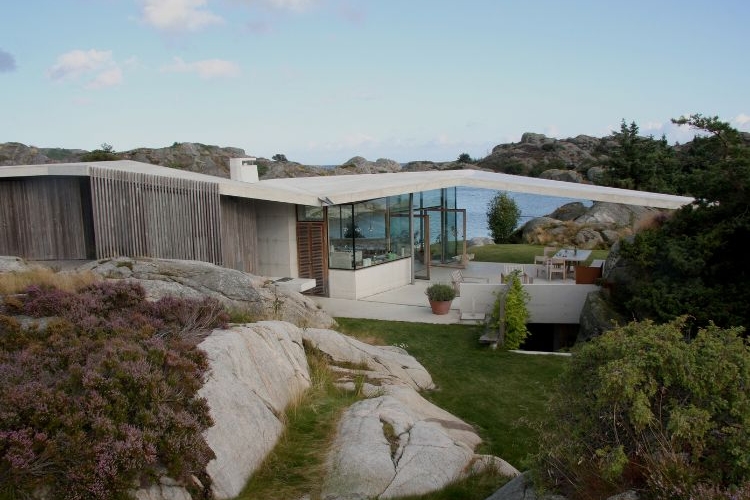 haus mit pultdach fjordhaus design felsen landschaft umgebung außenbereich gartenmöbel schräges dach aussicht abendsonne