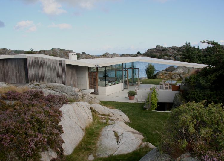 haus mit pultdach fjordhaus design felsen landschaft umgebung außenbereich gartenmöbel schräges dach aussicht abendsonne