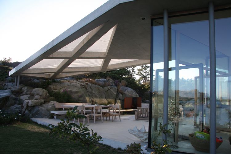 haus mit pultdach fjordhaus design felsen landschaft umgebung außenbereich gartenmöbel überdachung beton licht säulen
