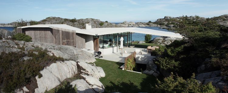 haus mit pultdach fjordhaus norwegen design felsen landschaft umgebung holzverkleidung beton glas meerblick überbrückung rasen