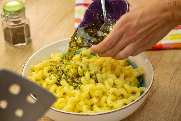 nudelsalat mit getrockneten tomaten gekochte pasta makkaroni dressing hineingeben gewürze