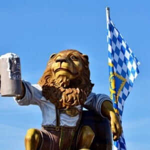 oktoberfest spiele löwe figur statue bierkrug fahne blau himmel