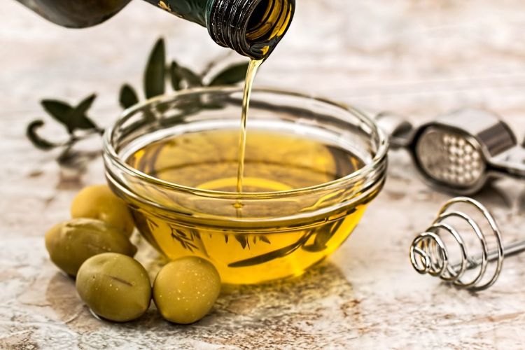 olivenöl zum braten nehmen glasflasche schüssel gießen oliven kochutensilien