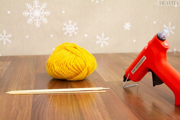 Holzstäbchen gelbes Wollgarn Heißklebepistole Bastelprojekt zu Weihnachten