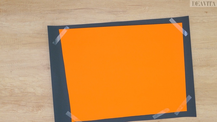 Orange und schwarzes Tonpapier mit Klebeband zusammen kleben