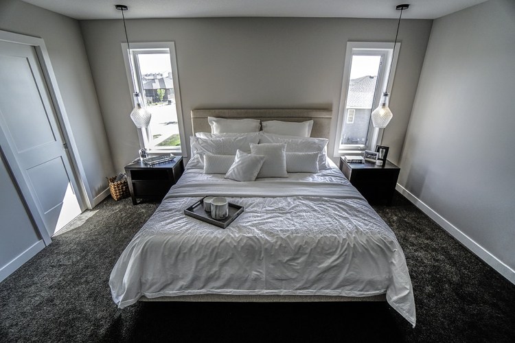 Schlafzimmer mit Teppichbodenbelag in Anthrazit Doppelbett graue Wandfarbe Pendelleuchten