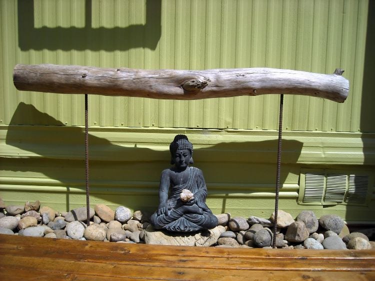 gartenkunst treibholz bohren stahlstäbe buddha figur steine blech wand sonnenlicht