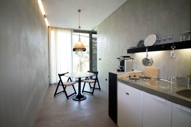 küche minimalistisch hängelampe stühle betonwände spülbecken herdplatten kaffeemaschine küchenutensilien