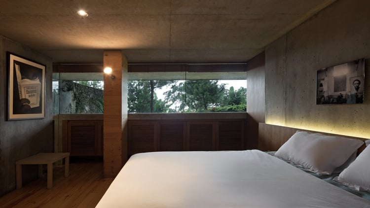 ferienhaus aus holz wald perfektes refugium wochenendhaus holzverkleidung betonwand bild bett schlafzimmer