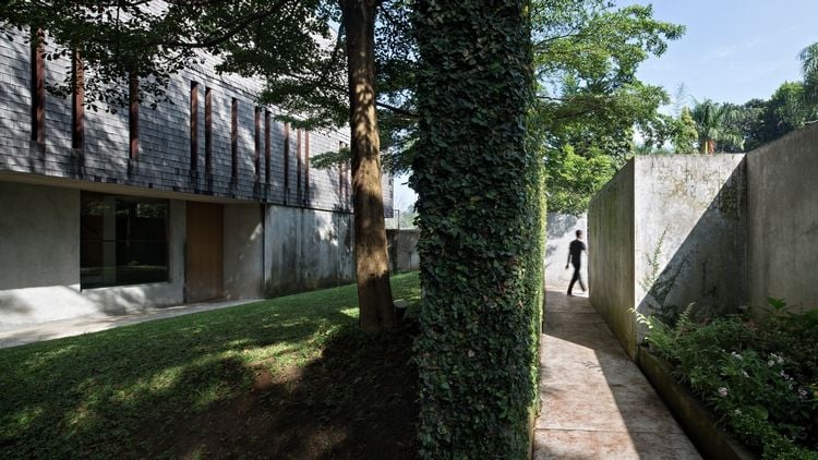ferienhaus aus holz wald perfektes refugium wochenendhaus holzverkleidung glasfassade pflanzen hinterhof beton mauer