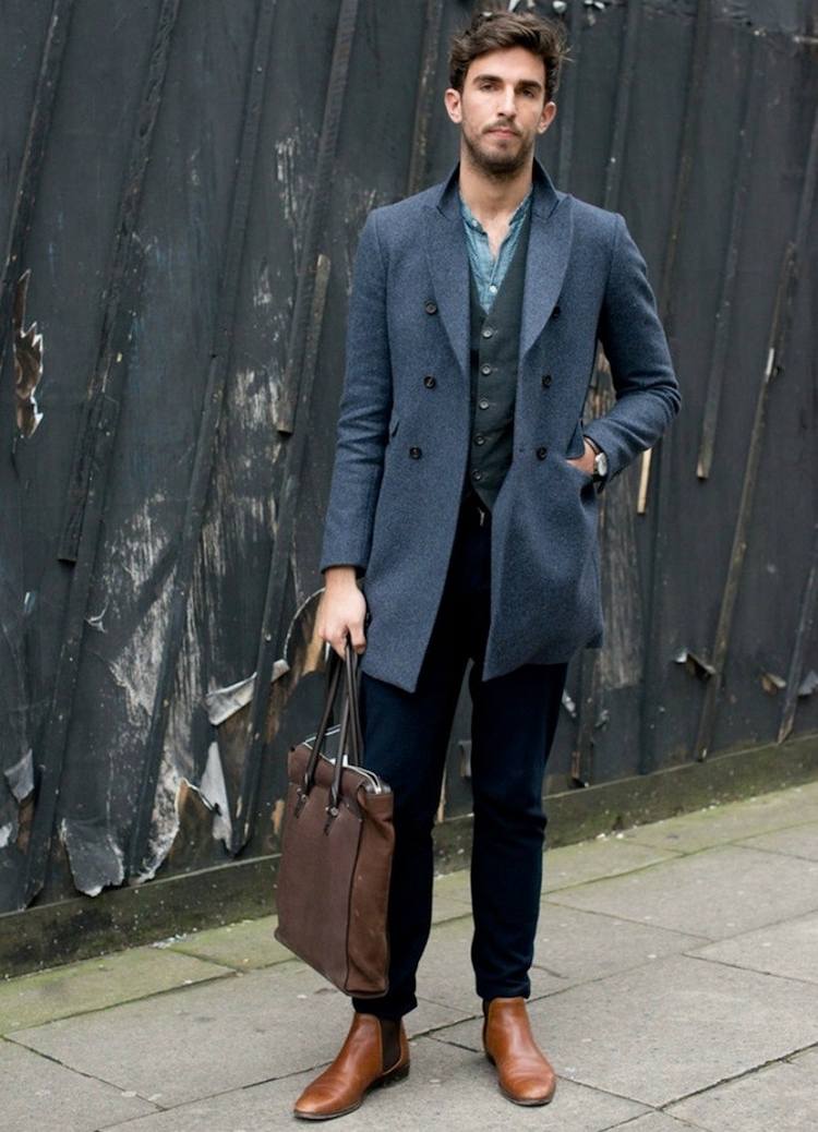 jeans stiefel kombinieren herren outfit oxford schuhe elegant aussehen braun mantel grau ledertasche chelsea boots weste jeanshemd
