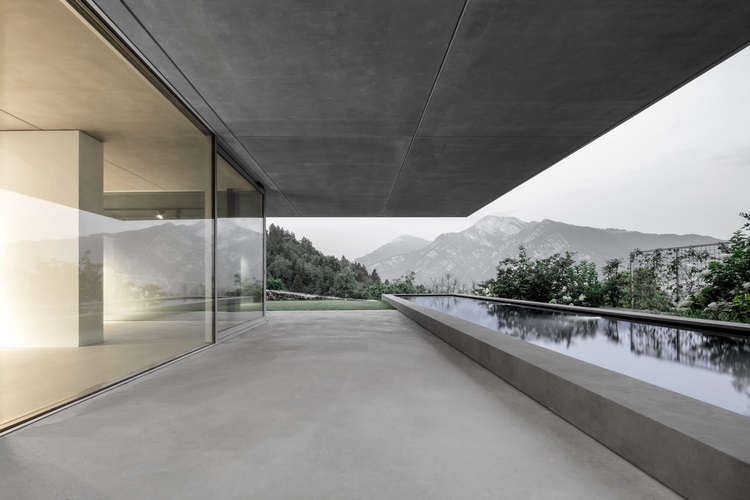 sichtbeton haus casa mf große glasfenster modernes minimalistisches design pool aussicht gebirge fenster