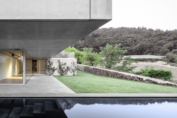 sichtbeton haus casa mf große glasfenster modernes minimalistisches design steinmauer wald glasschiebetür begrünung