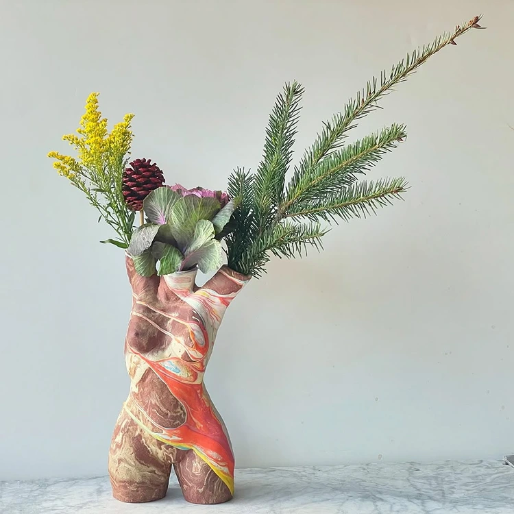 vase in form einer skulptur mit tannenzweigen fichtenzapfen und winterlichen blüten