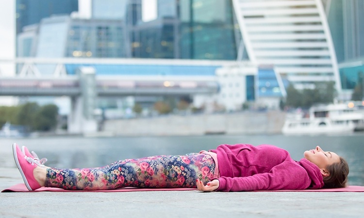 yoga-nidra-zum-einschlafen-praktische-einschlafübungen-besseren-schlaf-tiefentspannung-frau-draußen-liegen-schlafen-fluss-gebäude