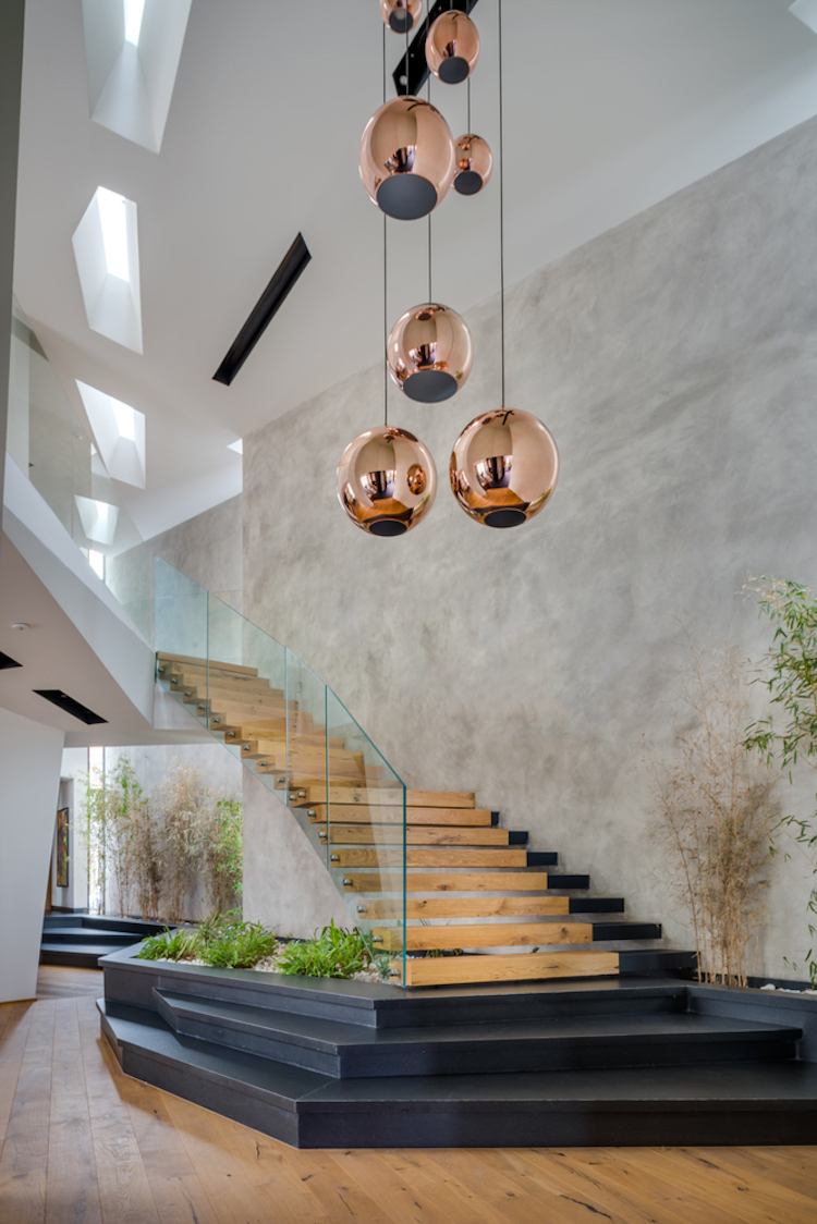 asymmetrische Treppe mit Glas Geländern Holzstufen Kupfer Pendelleuchten