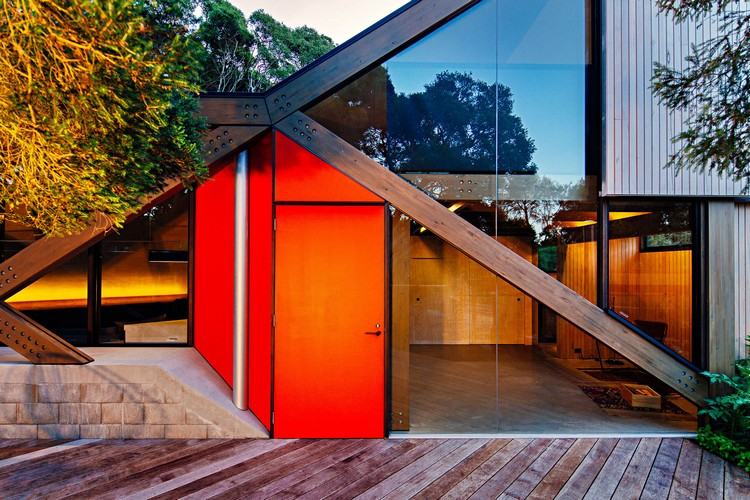 design ferienhaus schrägdach küstenwald moderne berghütte außergewöhnliche form holz veranda eingangstür glasfenster