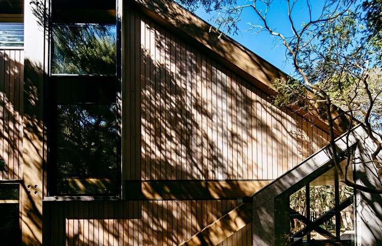 design ferienhaus schrägdach küstenwald moderne berghütte außergewöhnliche form schatten fassadenverkleidung rückseite