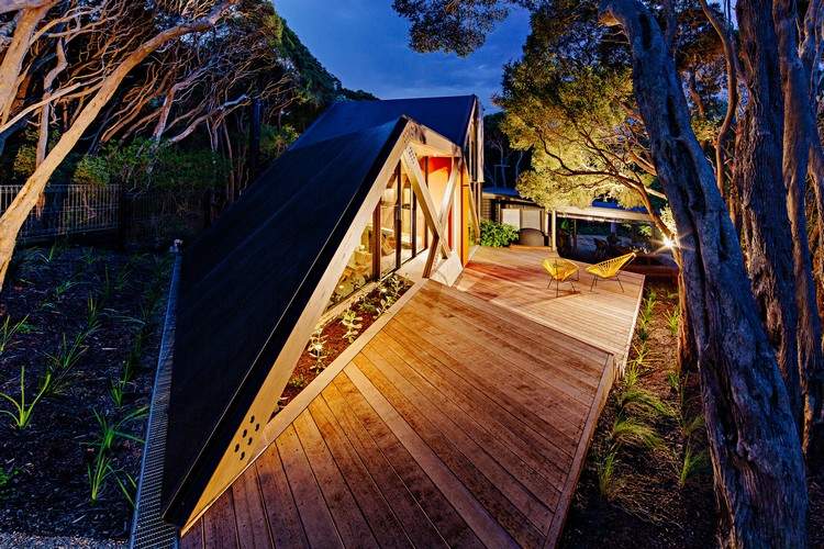 design ferienhaus schrägdach küstenwald moderne berghütte moonah bäume holz veranda beleuchtung