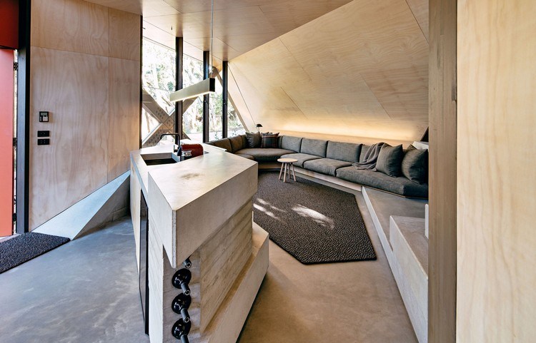 design ferienhaus schrägdach küstenwald moderne berghütte wohnzimmer theke waschbecken weinflaschen betonboden