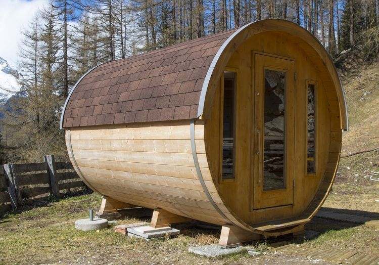 outdoor sauna bauen ideen designs entspannungsbereich im freien liegestühle baum blüten holz saunahäuschen rund glastür beschichtung