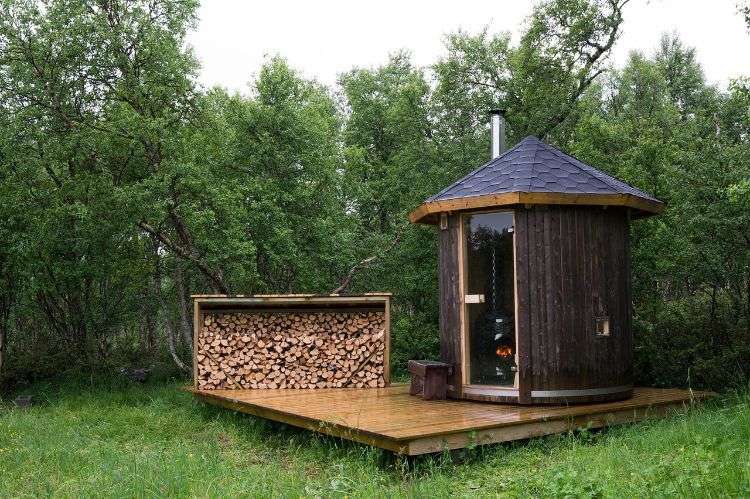 outdoor sauna bauen ideen designs entspannungsbereich im freien liegestühle baum blüten holz saunahäuschen rund klein schwarz garten