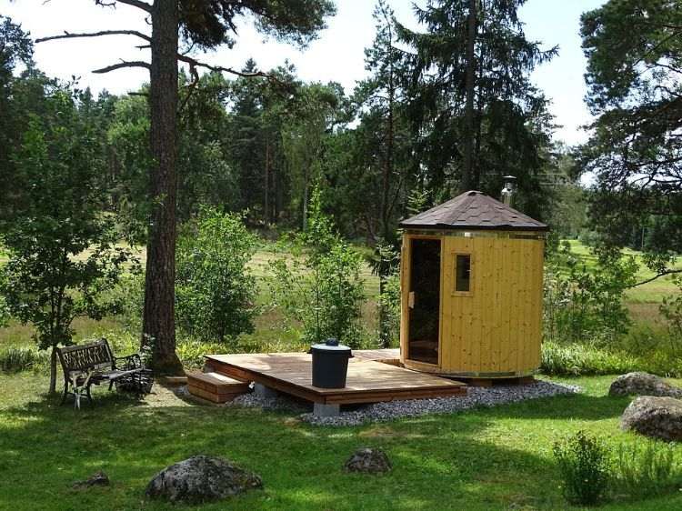 outdoor sauna bauen ideen designs entspannungsbereich im freien liegestühle baum blüten holz saunahäuschen rund klein wald garten