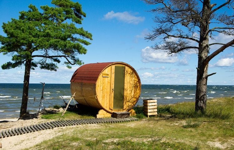 outdoor sauna bauen ideen designs entspannungsbereich im freien liegestühle baum blüten holz saunahäuschen rund küste meer wald