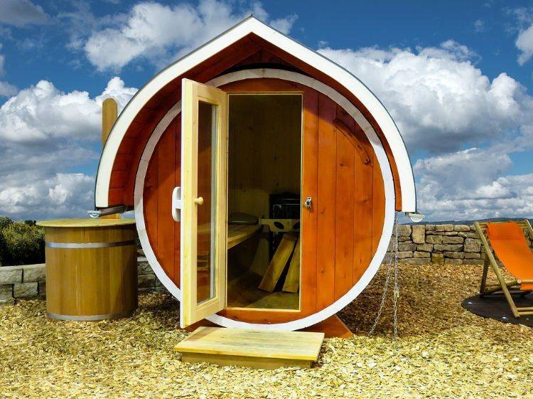 outdoor sauna bauen ideen designs entspannungsbereich im freien liegestühle baum blüten holz saunahäuschen rund tür