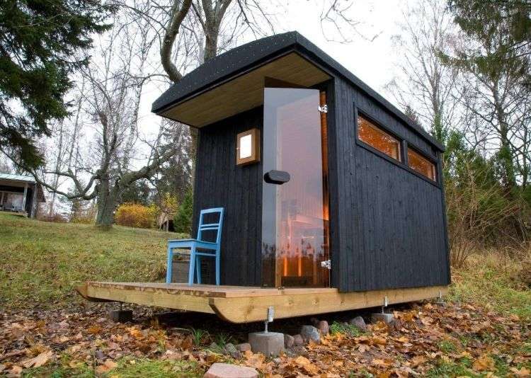 outdoor sauna bauen ideen designs entspannungsbereich im freien liegestühle baum blüten holz saunahäuschen schwarz blau stuhl wald