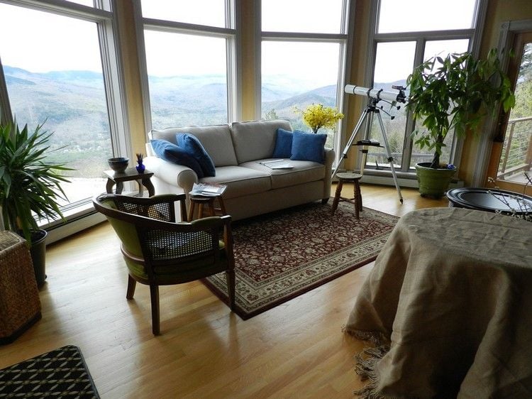 sofa vor fenster aufstellen wohnzimmer stilvoll couch orientalisch teppich palme fernrohr teleskop ausblick berge