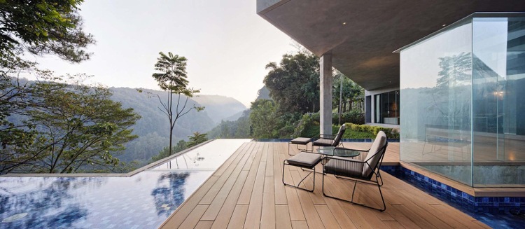 Holzterrasse mit Relaxsesseln und Infinity Pool