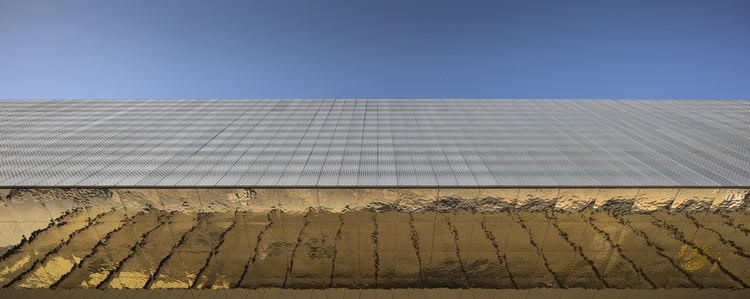 außenfassade mit goldenfarbigen platten aus kupfer spiegelnd