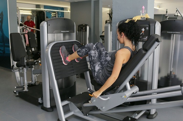 frau trainiert für beine mit gerät im fitnessstudio
