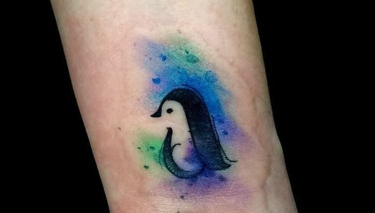 kleines Vogel Tattoo mit Pinguin und Aquarell-Effekt