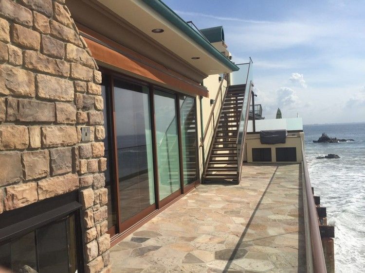 naturstein balkonboden ideen kombination mit braunen glasschiebetüren treppe meeresblick