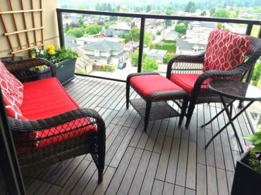 rattan stühle mit roten kissen holzdielen belegt am balkonboden fallschutz aus glas